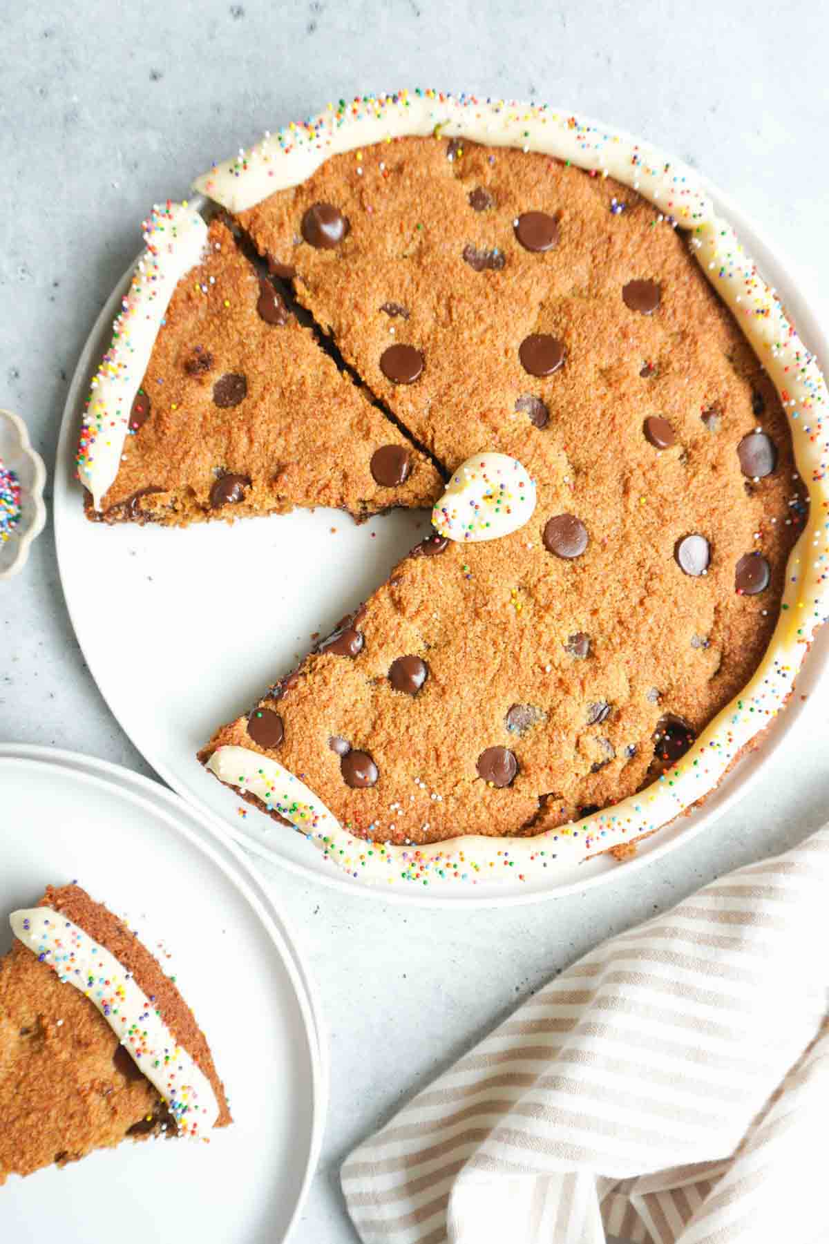 A giant chocolate chip cookie with icing and sprinkles.