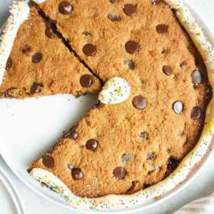 A giant chocolate chip cookie with icing and sprinkles.