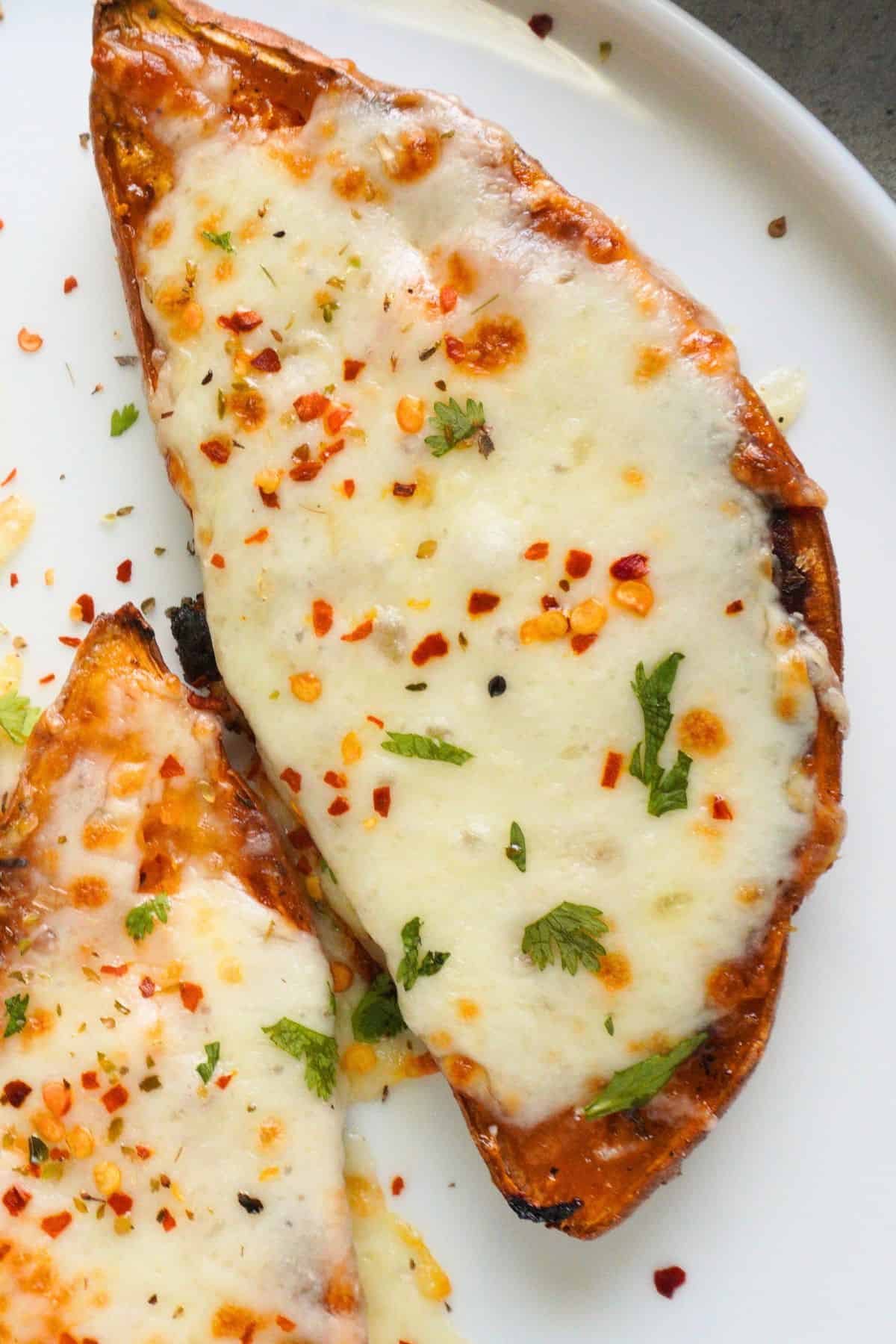 A sweet potato with melted mozzarella, crushed red pepper and parsley garnish.