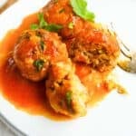 A white dish with chicken kofta curry and a fork.